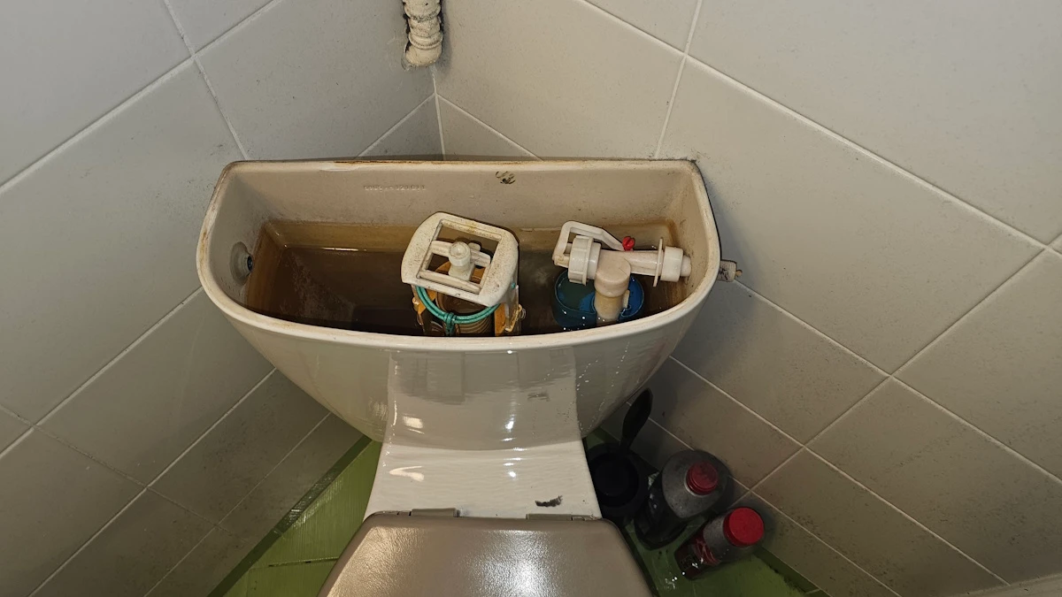 Otwarta spłuczka kompaktu WC z widocznym zaworem pływakowym i spustowym